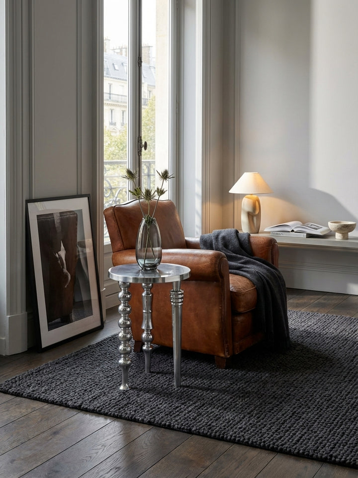 Der runde Alu-Abstelltisch harmoniert perfekt mit einem cremefarbenen Sofa und einem grob gewebten Teppich und schafft eine stilvolle Wohnatmosphäre._