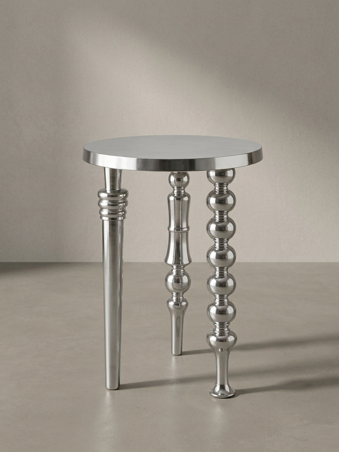 Seitenansicht des 63 cm hohen Aluminium-Beistelltisches, die seine schlanke Silhouette und die unterschiedlichen Profile seiner drei Standbeine zeigt._