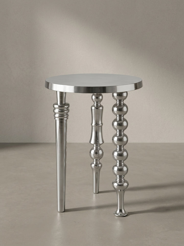 Seitenansicht des 63 cm hohen Aluminium-Beistelltisches, die seine schlanke Silhouette und die unterschiedlichen Profile seiner drei Standbeine zeigt._