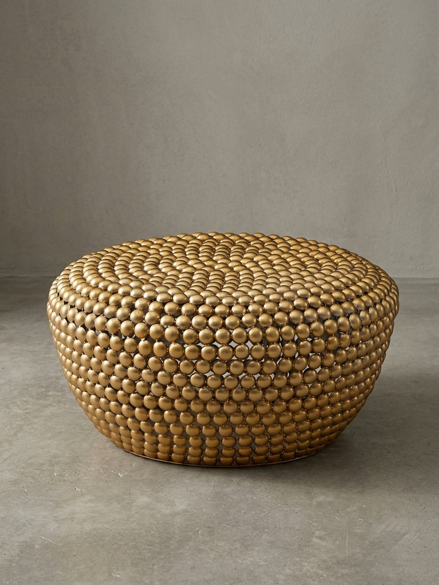 Runder Couchtisch aus goldfarbenem Aluminium mit genoppter Oberfläche, freigestellt vor weißem Hintergrund, Maße 60x30 cm, Frontalansicht._