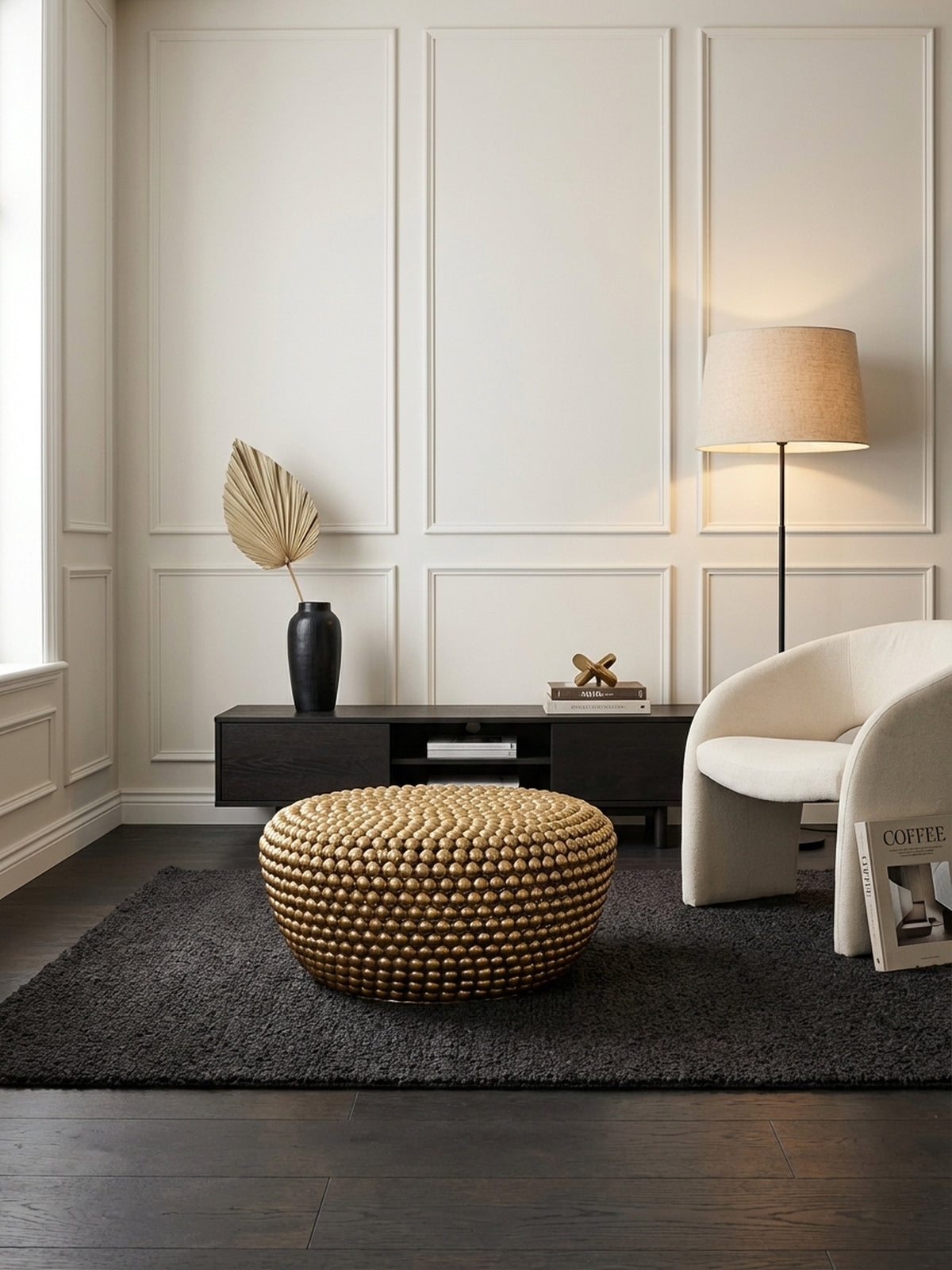 Eleganter runder Couchtisch in Gold als Blickfang in einem modern-klassischen Wohnzimmer, platziert auf einem dunklen Teppich vor einem Ledersofa.