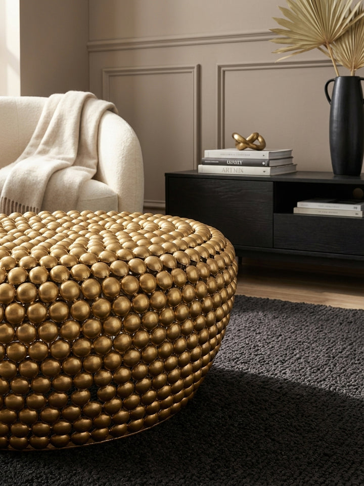 Makroaufnahme der goldenen genoppten Oberfläche eines orientalischen Couchtisches aus Metall, die handwerkliche Textur und das matte Finish des Aluminiums zeigend._