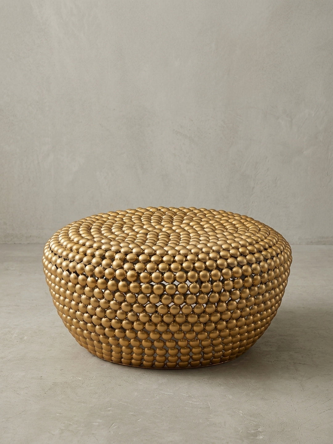 Dreiviertelansicht des goldenen Couchtischs, der die skulpturale Form und das einzigartige Design der genieteten Aluminium-Oberfläche hervorhebt._