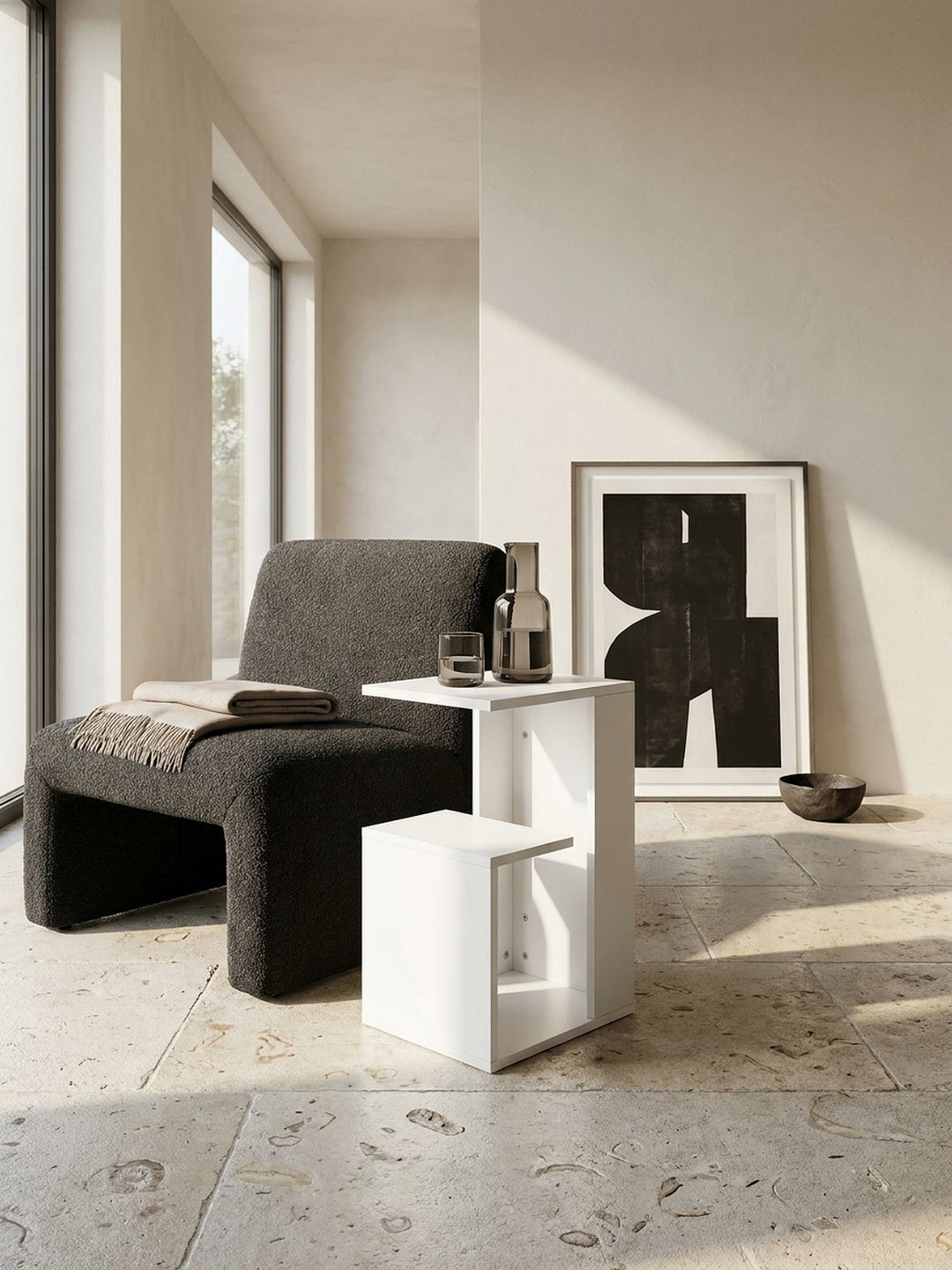 Weißer C-Form Sofatisch im architektonischen Zusammenspiel mit einem dunklen Bouclé-Sessel und einer dezent fließenden Kaschmirdecke_
