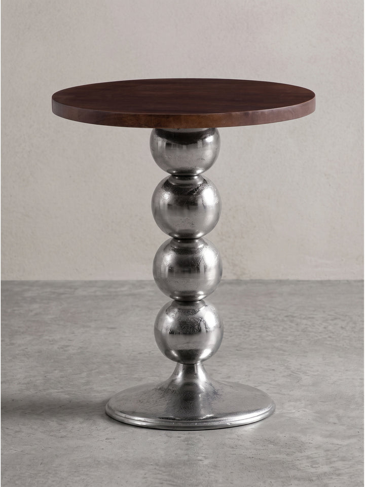 Vorderansicht des runden Beistelltischs aus Mango Massivholz mit markantem Kugel-Standbein aus silbernem Aluminium vor weißem Hintergrund._
