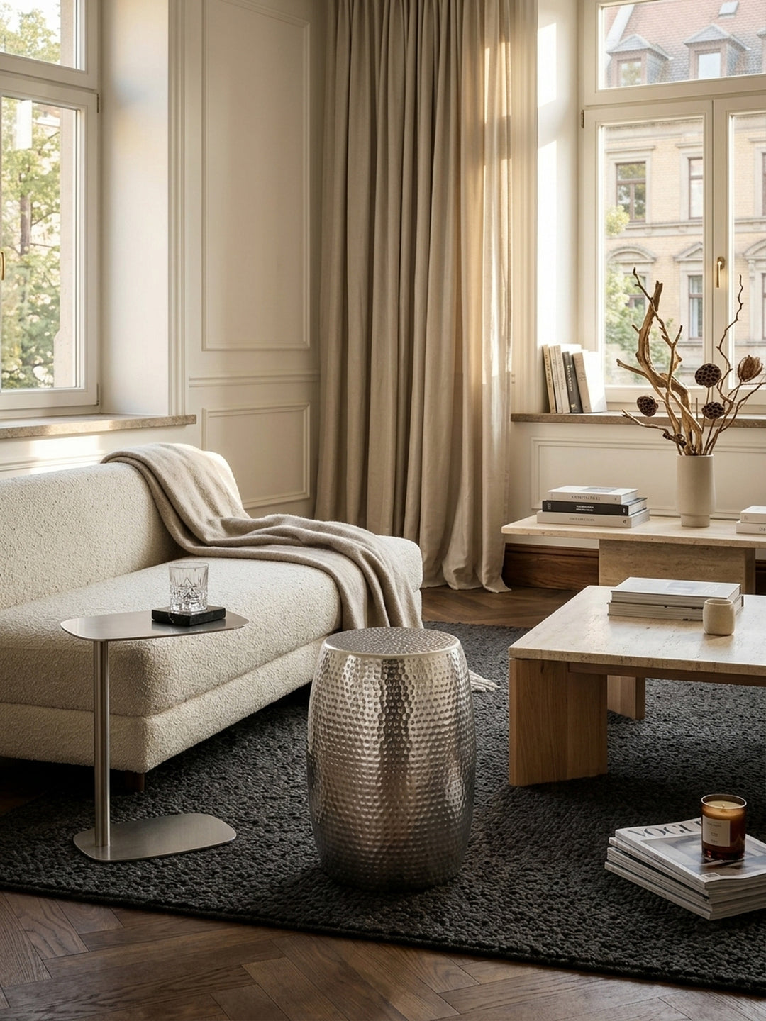 Draufsicht auf den kleinen Hammerschlag Dekotisch in Silber, 30x30cm runde Ablagefläche für Getränke oder Bücher neben einer Couch im luxuriösen Interieur._