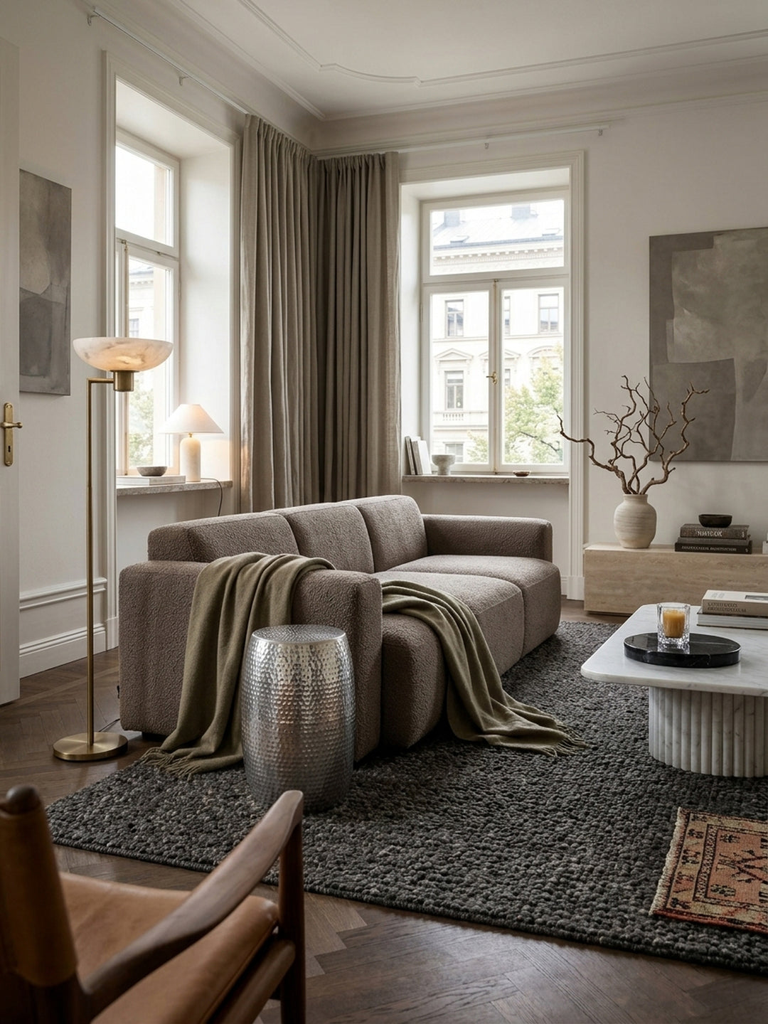 Runder silberner Beistelltisch aus Aluminium mit Hammerschlag-Optik im eleganten Wohnzimmer neben einem modernen Sessel auf dunklem Teppichboden, 49cm hoch._