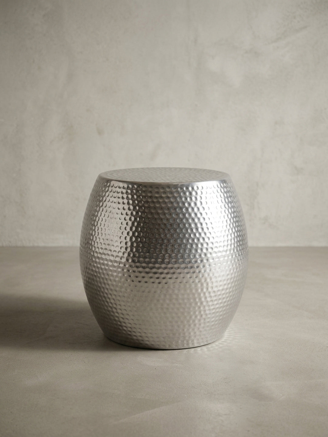 Alternative Perspektive des silbernen Hammerschlag Beistelltisches. Die leicht gewölbte Form des runden Aluminium Anstelltisches reflektiert das einfallende Licht elegant._
