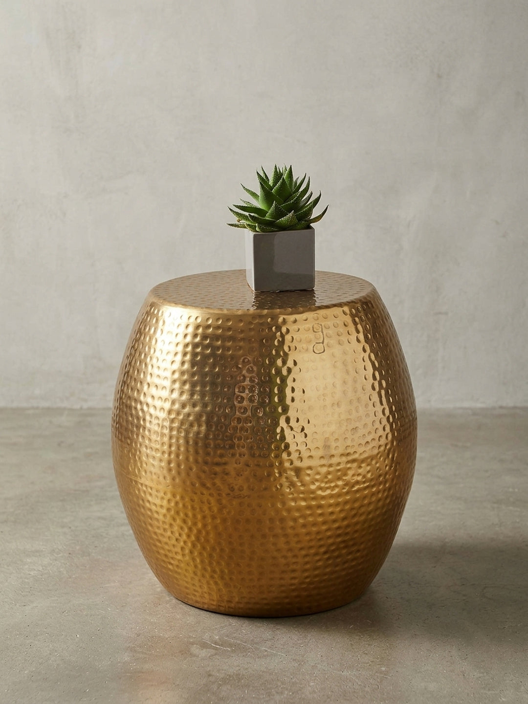 Orientalischer Beistelltisch in glänzendem Gold vor weißem Hintergrund. Der 42x42x42 cm große Aluminium-Tisch besticht durch seine markante, bauchige Fass-Silhouette._