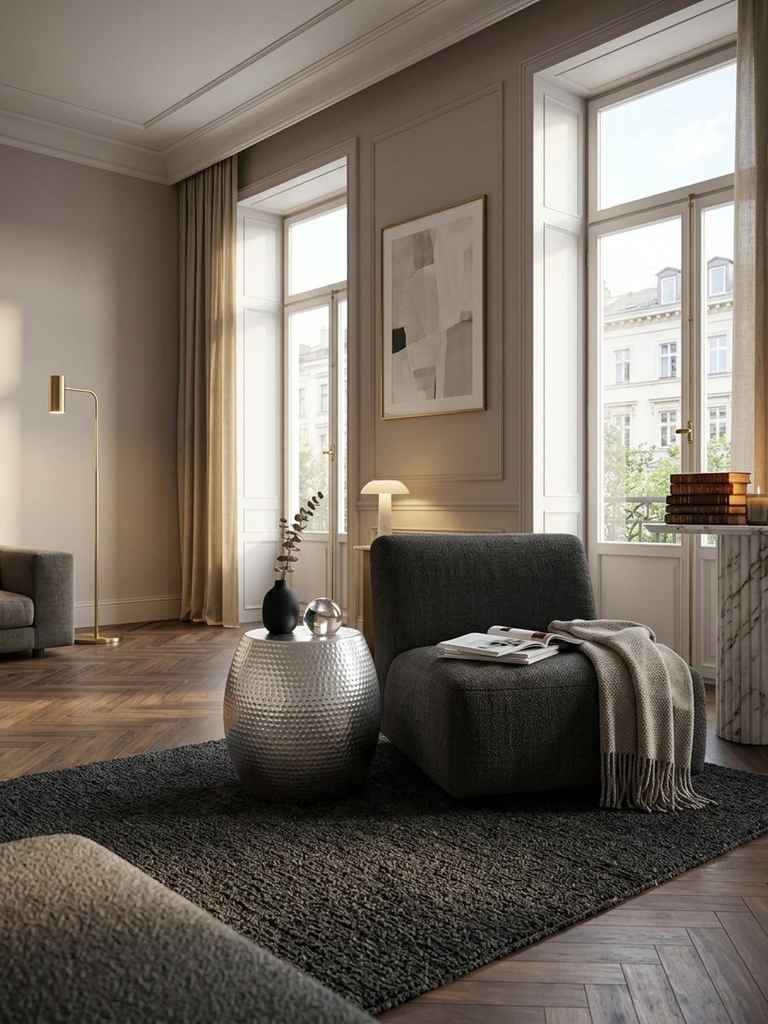 Silberner Aluminium Beistelltisch im edlen Wohnzimmer. Der orientalische Hammerschlag Couchtisch glänzt neben einem dunklen Sessel auf hochwertigem Walnussparkett._