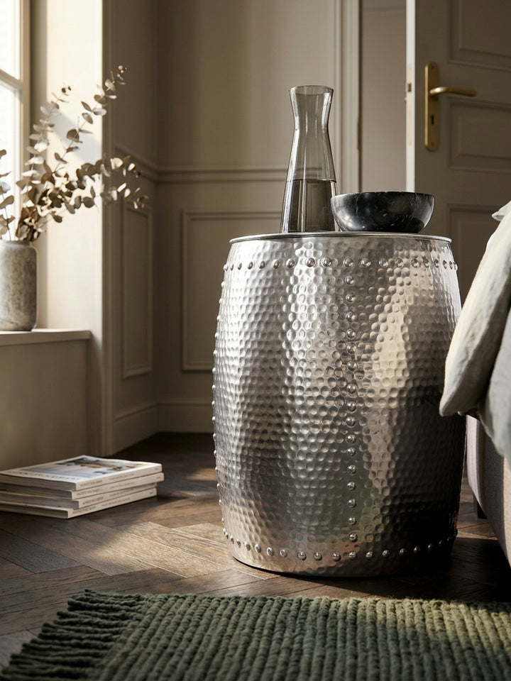 Detailaufnahme der silbernen Aluminiumoberfläche. Das handgefertigte Hammerschlag-Design zeigt feine, in Linien angeordnete Erhöhungen, die dem Beistelltisch seine Textur verleihen._