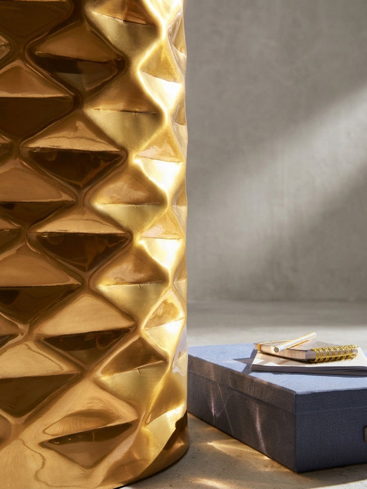 Aus leicht erhöhter Perspektive präsentiert sich der orientalische goldene Metalltisch, wobei der Kontrast zwischen flacher Ablagefläche und geometrisch geformtem Korpus deutlich wird._