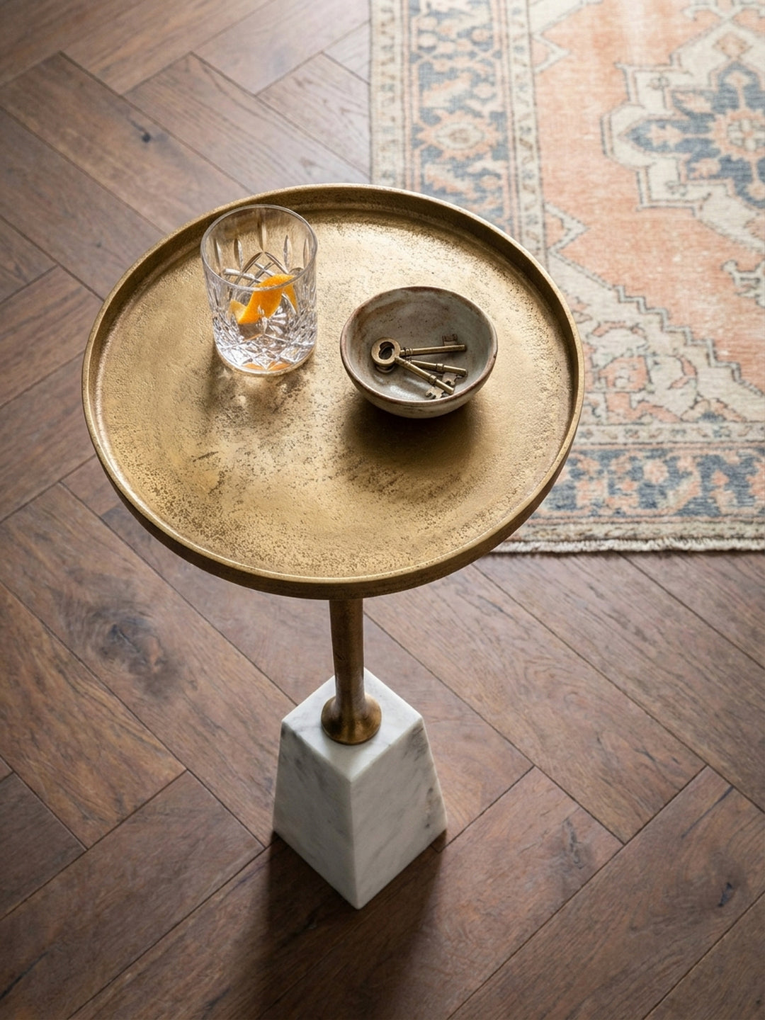 Runder Anstelltisch aus Metall in Gold und Marmor von oben gesehen, arrangiert mit einem Sessel auf einem Vintage-Teppich._