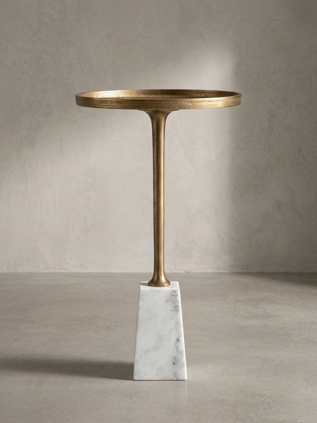 Detailaufnahme des Übergangs vom schlanken, goldenen Tischbein zum schweren, präzise gefertigten Sockel aus echtem Marmor._