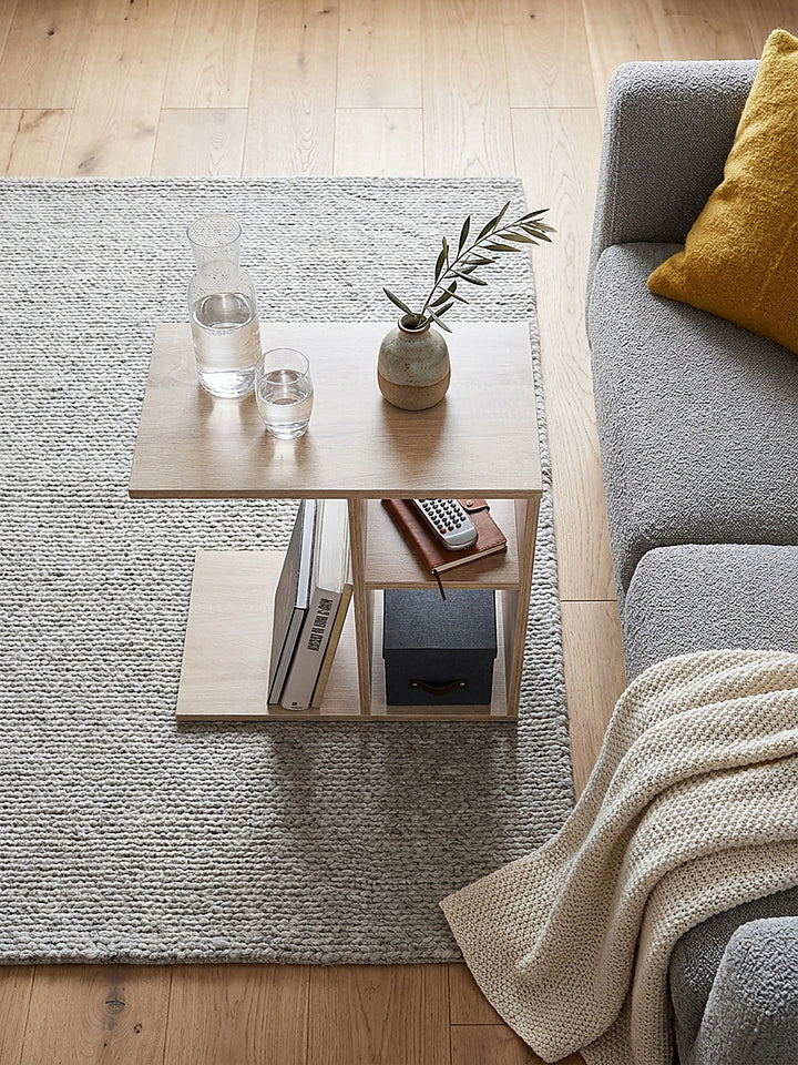 Ansicht von oben auf den C-förmigen Anstelltisch aus heller Holzoptik neben einem grauen Polstersofa auf Eichenparkett_