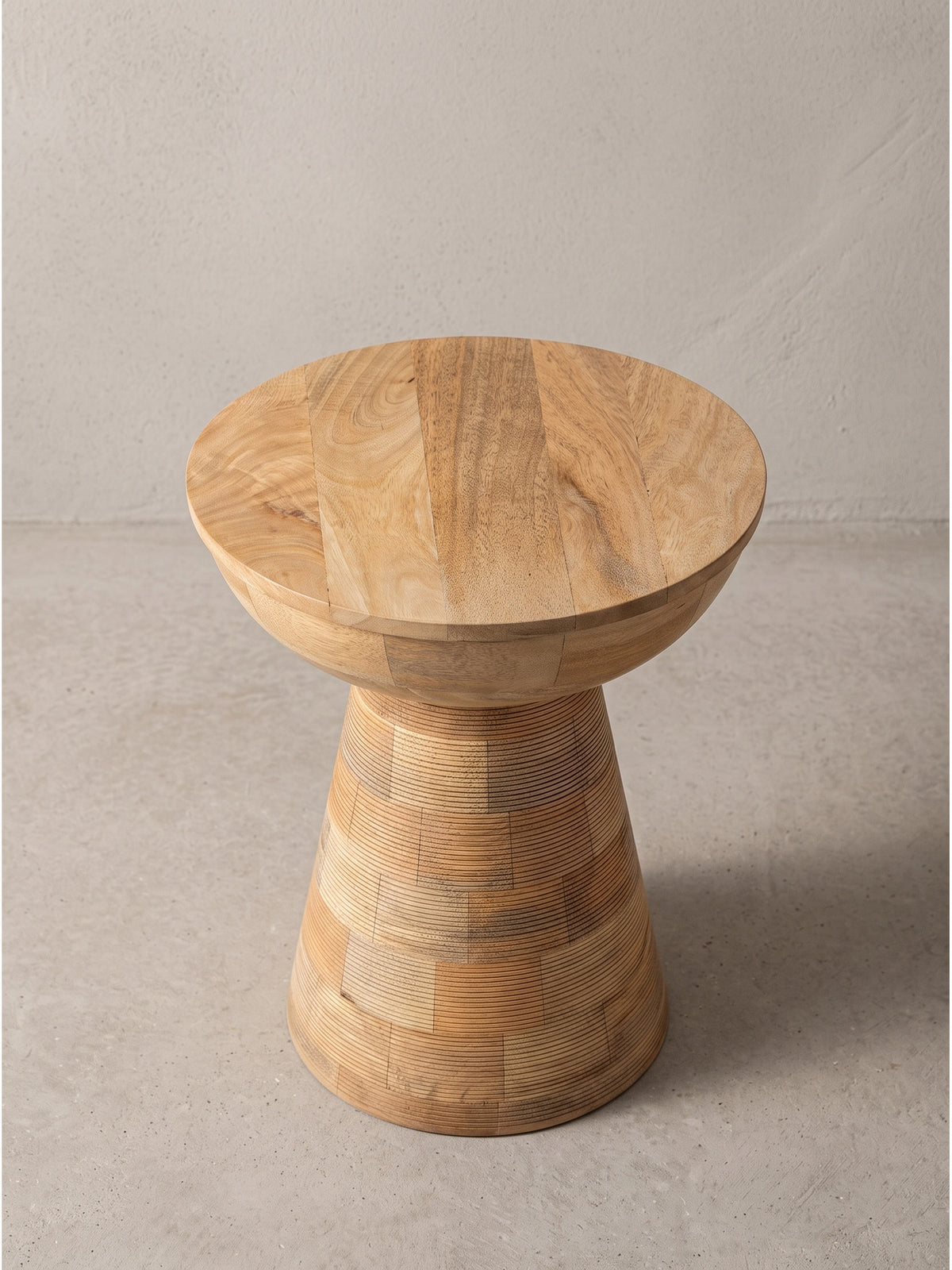 Leicht seitliche Perspektive auf den Massivholz Beistelltisch aus hellem Mangoholz, die sanft geschwungene Schalenform der 37 cm breiten Tischplatte ist deutlich erkennbar