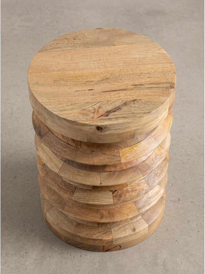 Leicht schräge Perspektive des runden Abstelltisches aus hellem Holz, die die präzise handwerkliche Verarbeitung der markanten Rundungen hervorhebt._