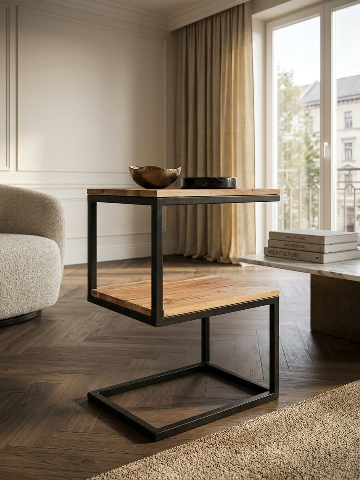 Detailansicht der massiven Akazienholzplatte des Ablagetisches. Deutlich erkennbar sind die lebhafte Holzmaserung und die mattschwarze Pulverbeschichtung des Metallrahmens._