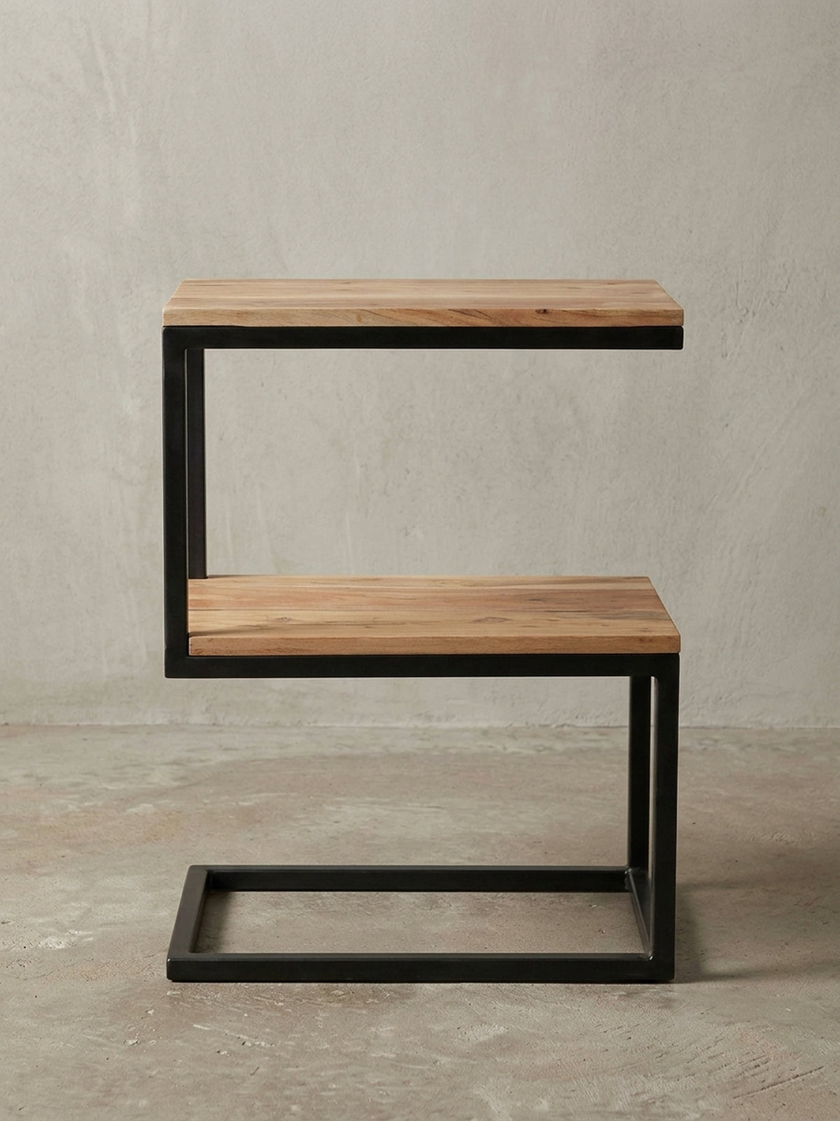 Freigestellter Beistelltisch in markanter S-Form. Das schwarze Metallgestell und die zwei Ablageflächen aus massivem Akazienholz zeigen klares Design für moderne Wohnzimmer.