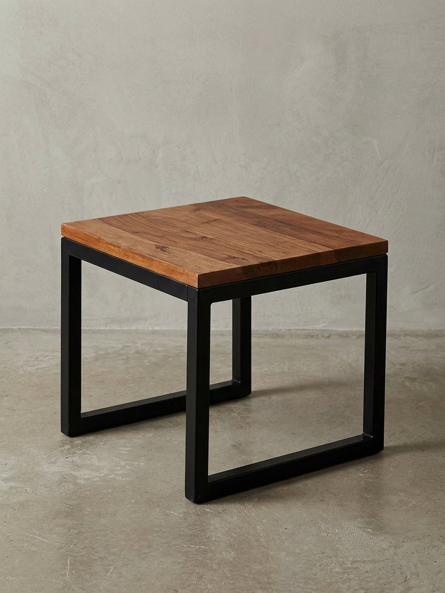 Freigestellter Beistelltisch im Industrial Style mit einer massiven Sheesham-Holzplatte und einem kubischen, schwarzen Metallgestell, Frontansicht auf weißem Hintergrund._