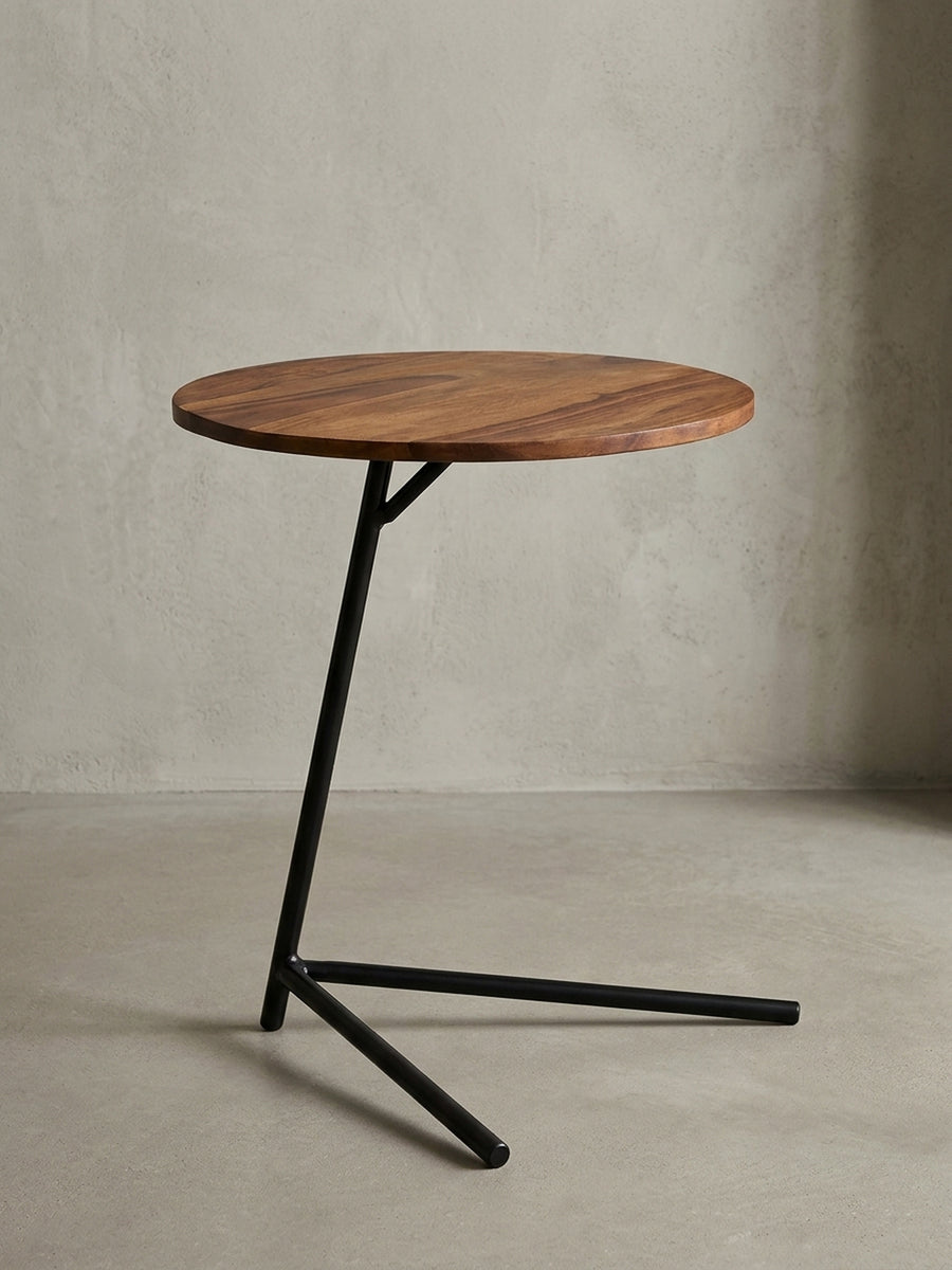 Frontansicht des 46cm hohen Beistelltisches auf weißem Hintergrund. Die runde Massivholzplatte aus dunklem Palisander ruht auf einem filigranen, V-förmigen schwarzen Metallgestell._