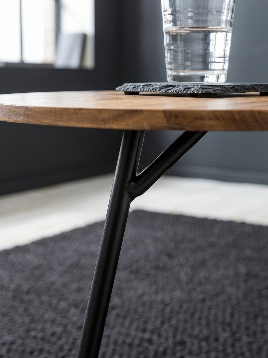 Nahaufnahme der edlen Sheeshamholz Oberfläche des Beistelltisches. Die feine, natürliche Holzmaserung harmoniert perfekt mit dem mattschwarz lackierten Metall des Industrial Couchtischs._