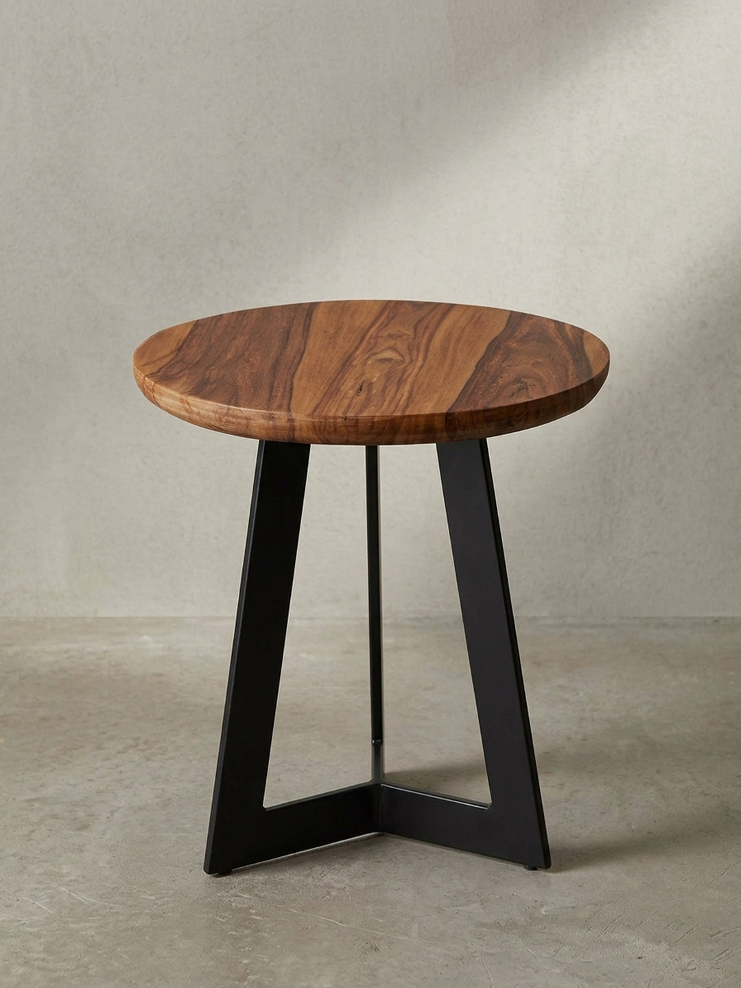 Niedriger Holztisch im industriellen Stil mit 35 cm Durchmesser und schwarz lackierten Eisenbeinen in leicht seitlicher Ansicht._