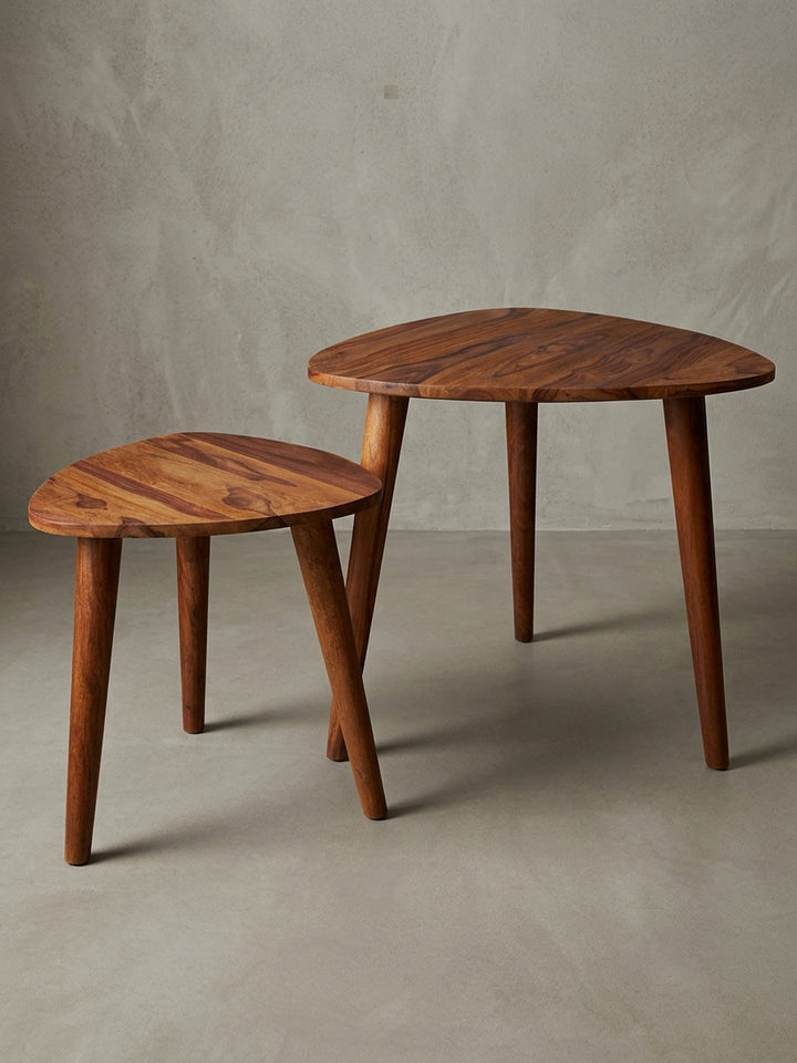 Zweiteiliges Couchtisch-Set aus massivem Sheeshamholz vor weißem Hintergrund. Die dreieckigen, abgerundeten Tischplatten ruhen auf stabilen, konisch geformten Massivholzbeinen._