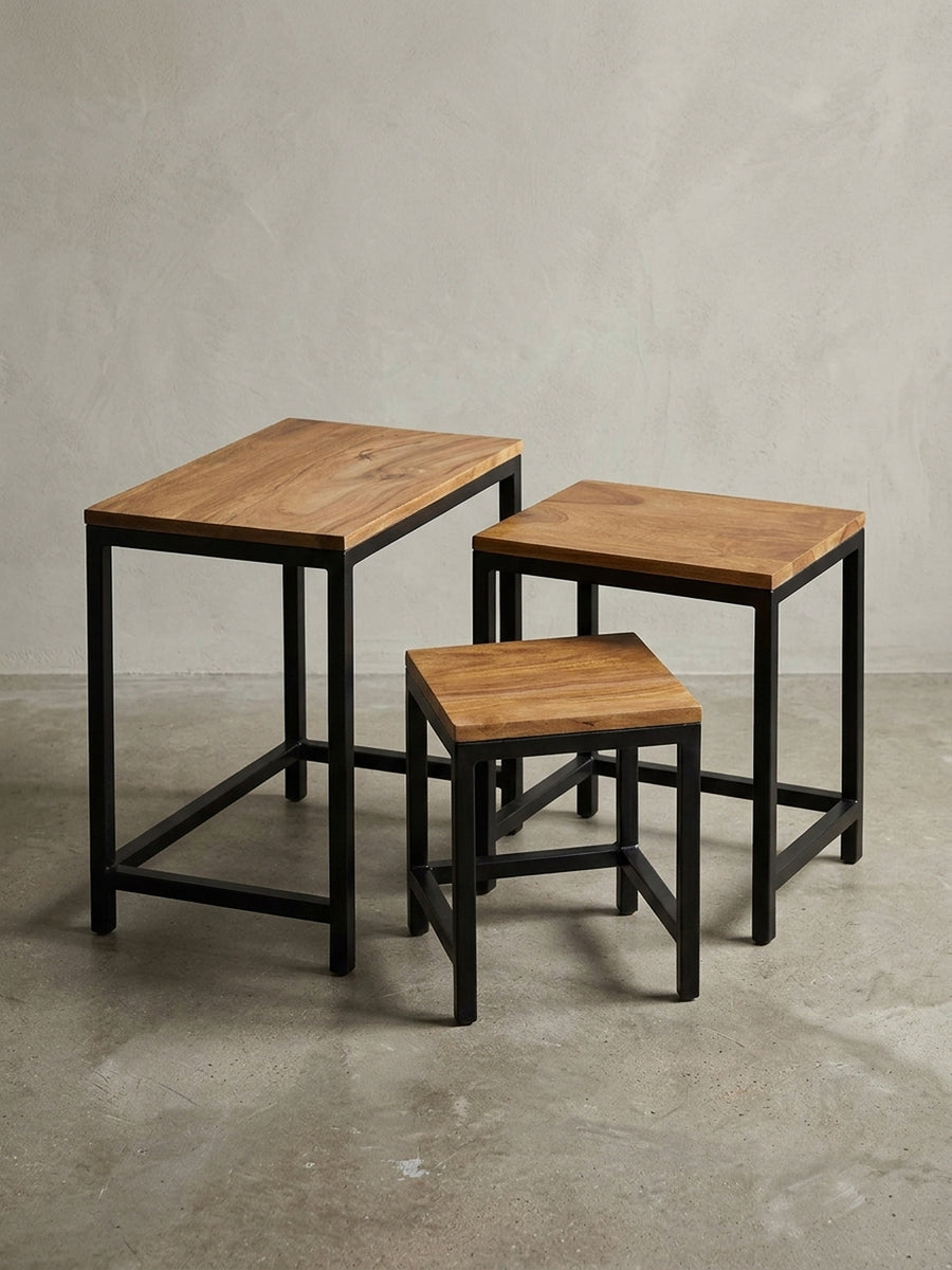 Dreiteiliger Beistelltisch mit schwarzem Vierfußgestell aus pulverbeschichtetem Metall. Die warme Massivholzplatte aus Sheesham bietet eine pflegeleichte und robuste Ablagefläche._