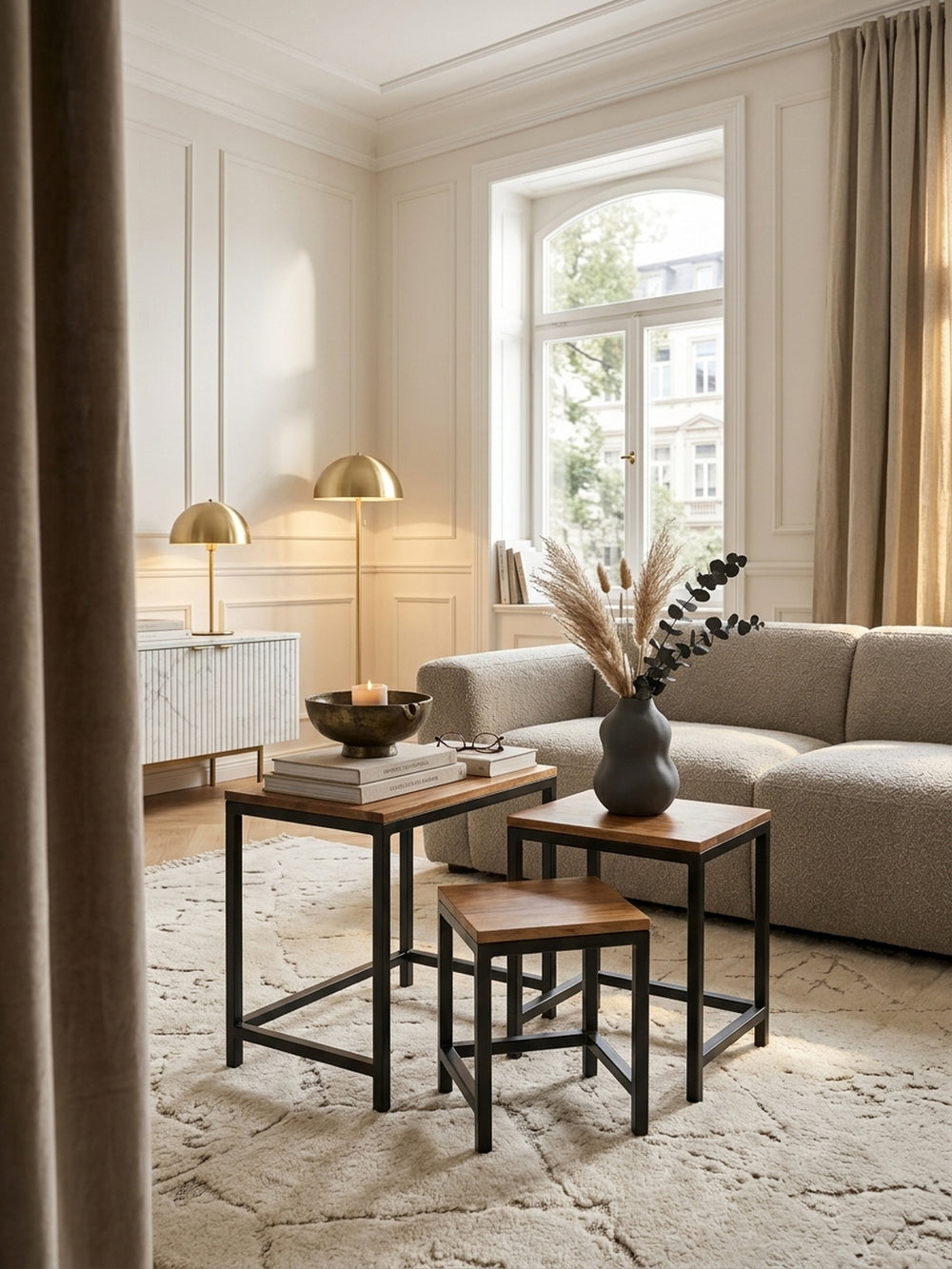 Eleganter Beistelltisch aus Sheesham Massivholz im Set neben einem hellen Sofa im Wohnzimmer. Das schwarze Metallgestell harmoniert mit dem Eichenparkett und der warmen Wandfarbe._