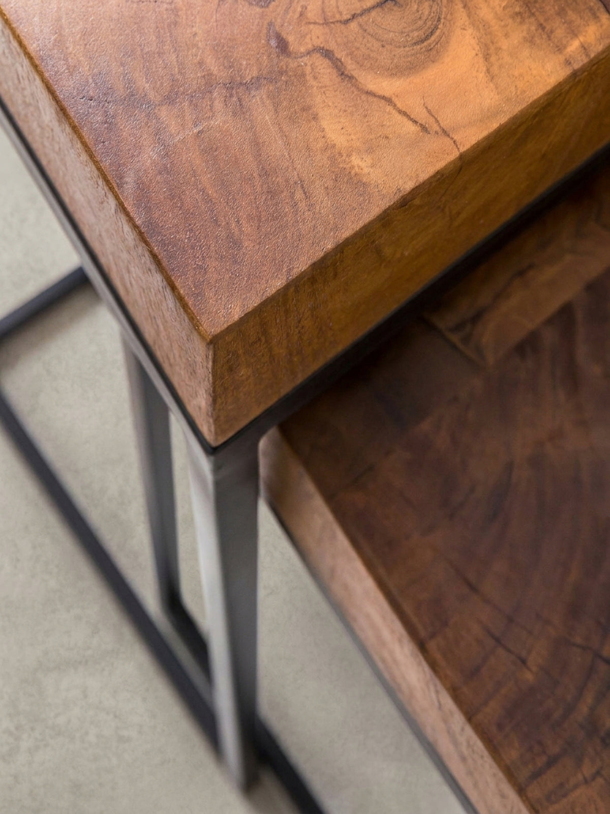 Gesamtübersicht der zwei ineinandergeschobenen Massivholz Beistelltische. Das minimalistische Industrie-Design des Wohnzimmertisches wirkt durch die Naturholz-Maserung besonders exklusiv.