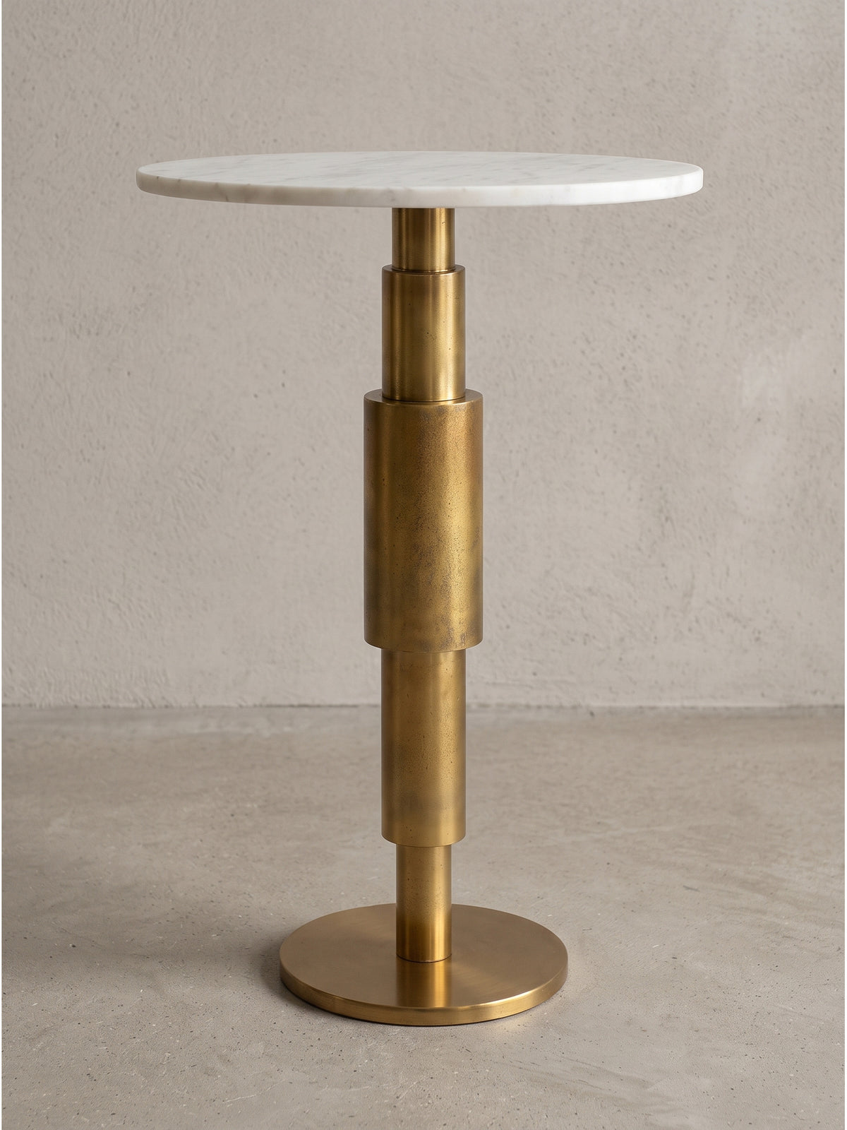 Freigestellter Beistelltisch mit runder weißer Marmorplatte und säulenartigem Aluminiumgestell in eleganter Goldoptik in der Frontalansicht_
