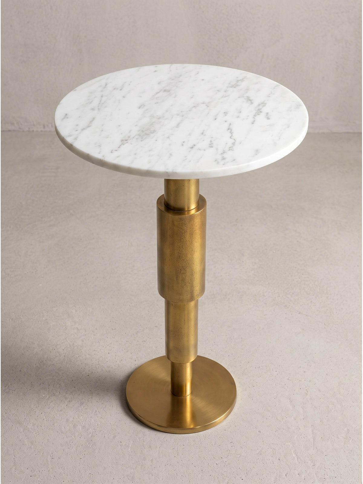 Runder Dekotisch 37x37x59 cm mit skulpturalem Metallfuß und heller Steinoberfläche fotografiert im Studio aus leicht erhöhter seitlicher Perspektive