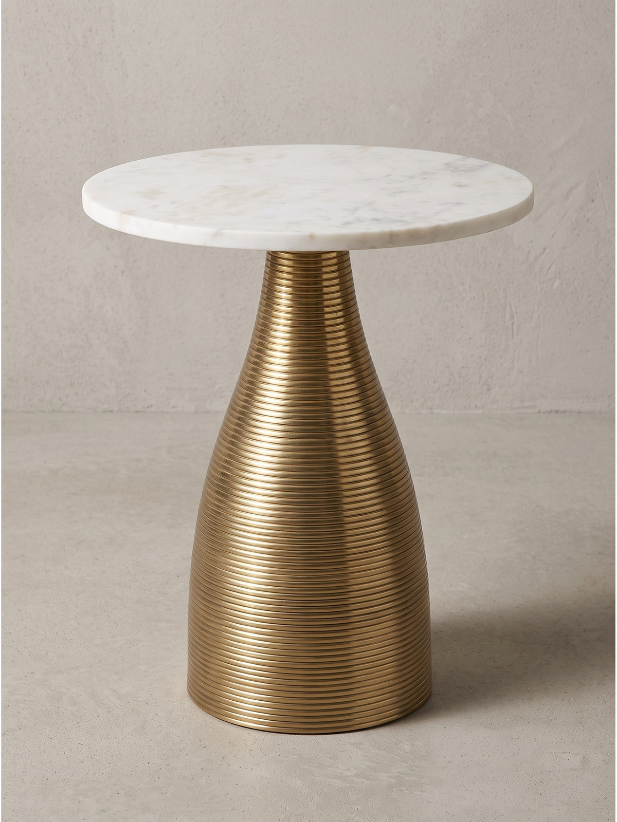 Nahaufnahme des filigranen Übergangs vom geriffelten goldenen Aluminiumgestell zur glatten massiven Marmorplatte_