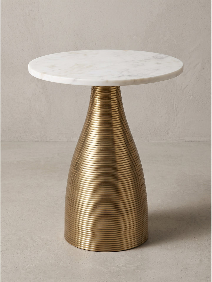 Nahaufnahme des filigranen Übergangs vom geriffelten goldenen Aluminiumgestell zur glatten massiven Marmorplatte_