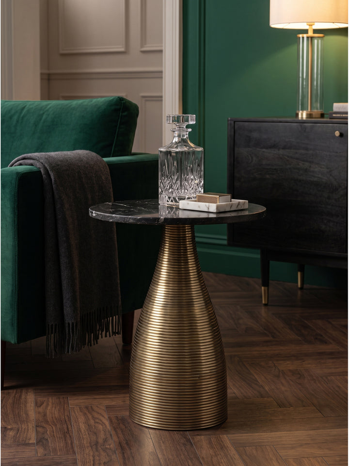 Dekorativer Anstelltisch in Gold und Schwarz mit einer schweren Kristallkaraffe und einem Marmortablett im stilvollen Wohnzimmer, sanft beleuchtet durch eine warme Messing-Stehlampe._
