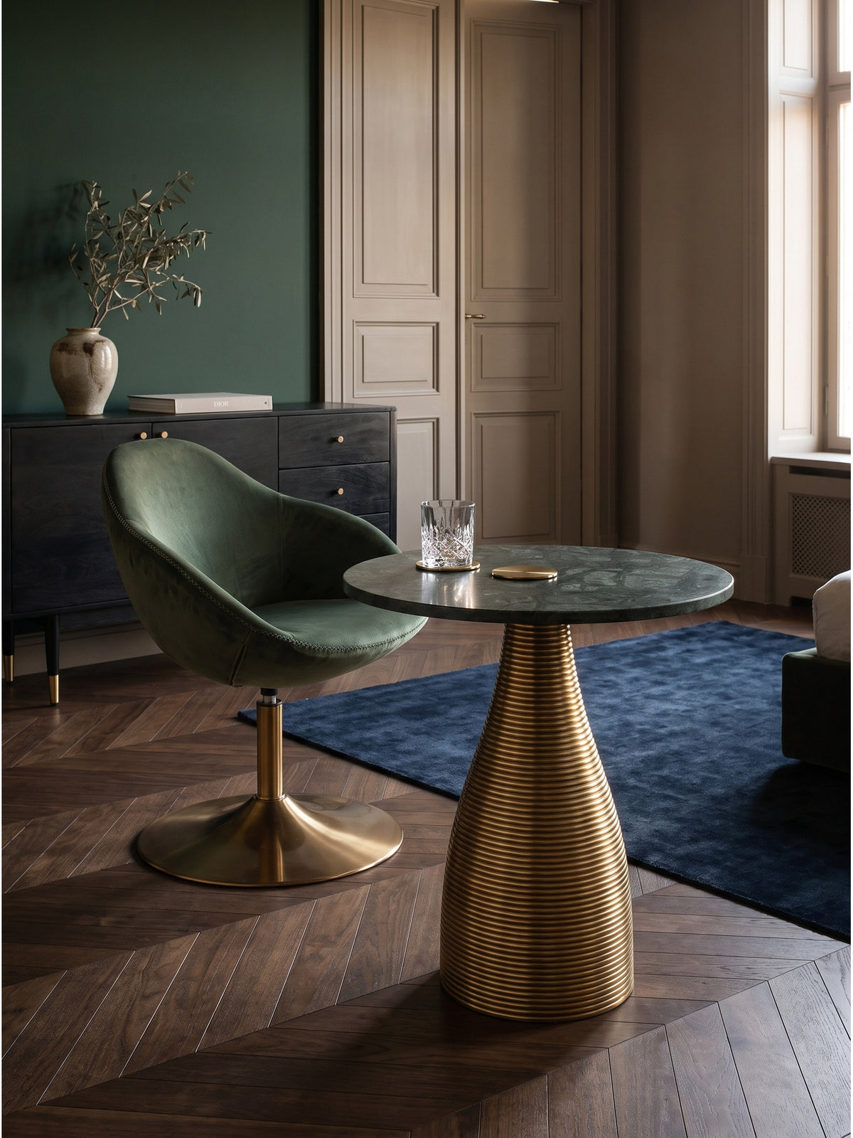 Design Anstelltisch aus Metall und Marmor arrangiert mit einem dunkelgrauen Sessel auf dunklem Nussholzparkett