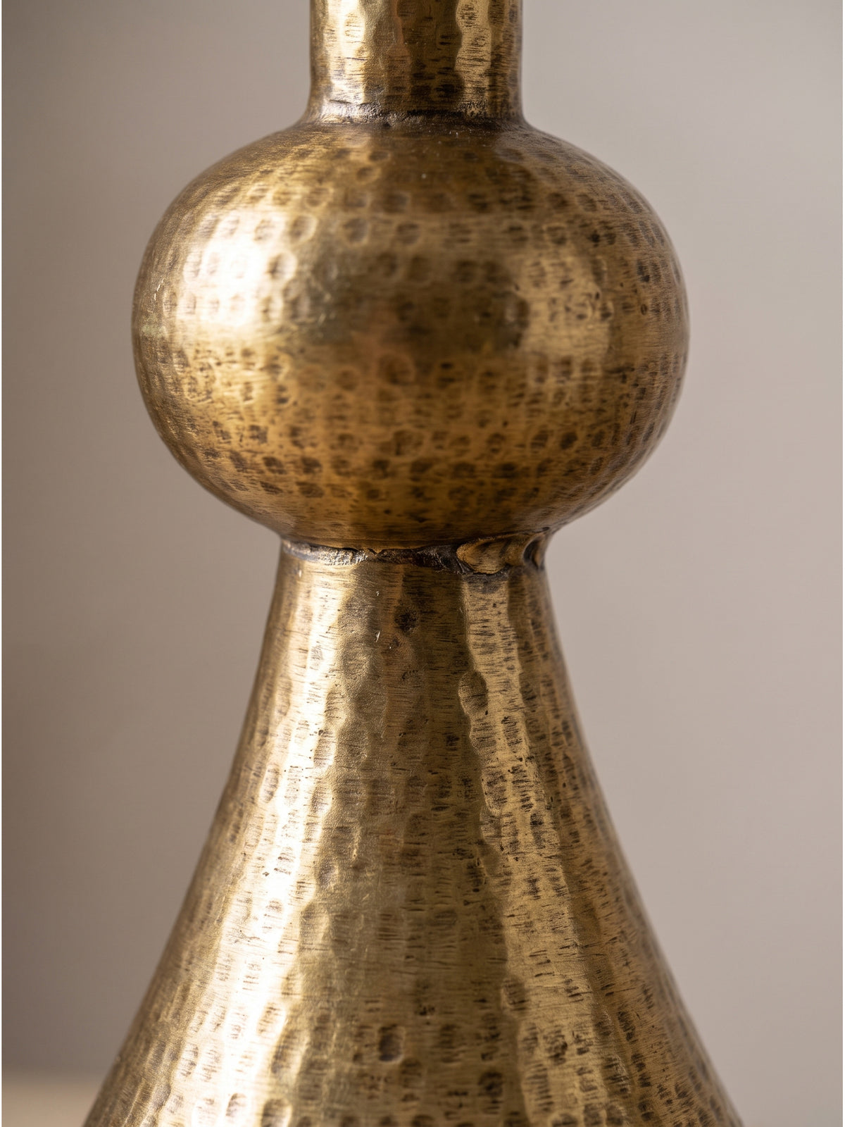 Nahaufnahme der feinen Ringstruktur und der gehämmerten Oberfläche des goldenen Aluminiumtisches mit handwerklich gefertigter antiker Patina._