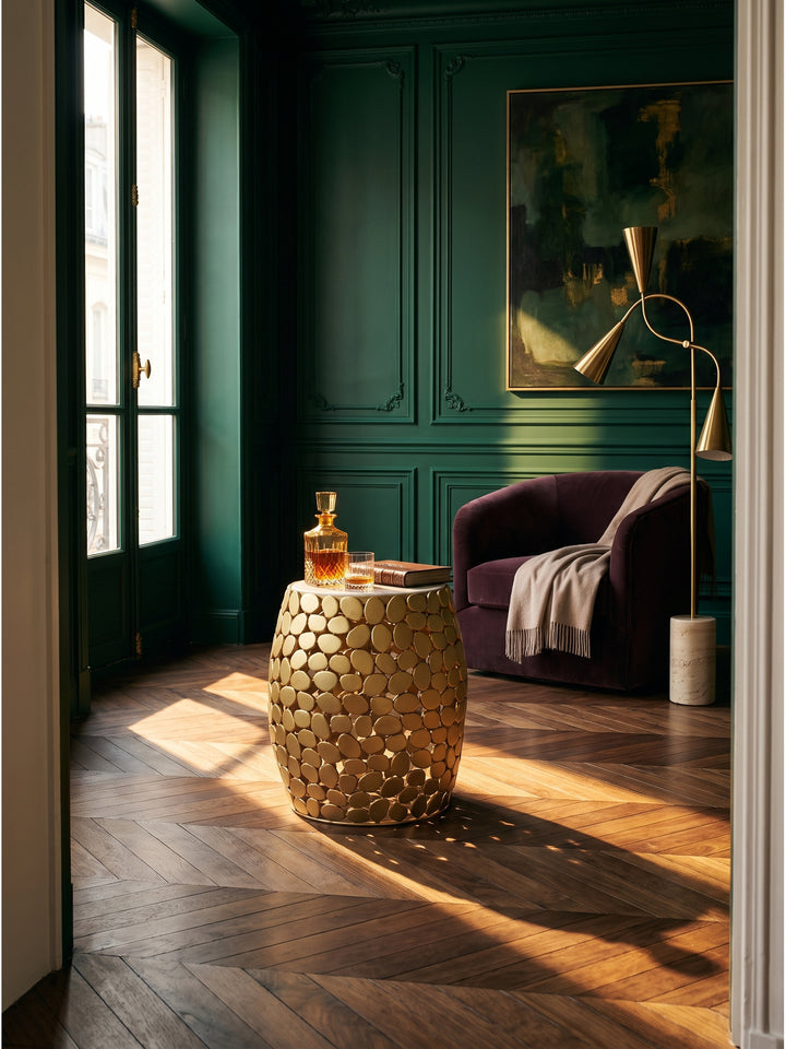 Goldener Beistelltisch mit weißer Marmorplatte im eleganten Art-Deco Wohnzimmer neben einem pflaumenfarbenen Samtsessel auf dunklem Walnussparkett._