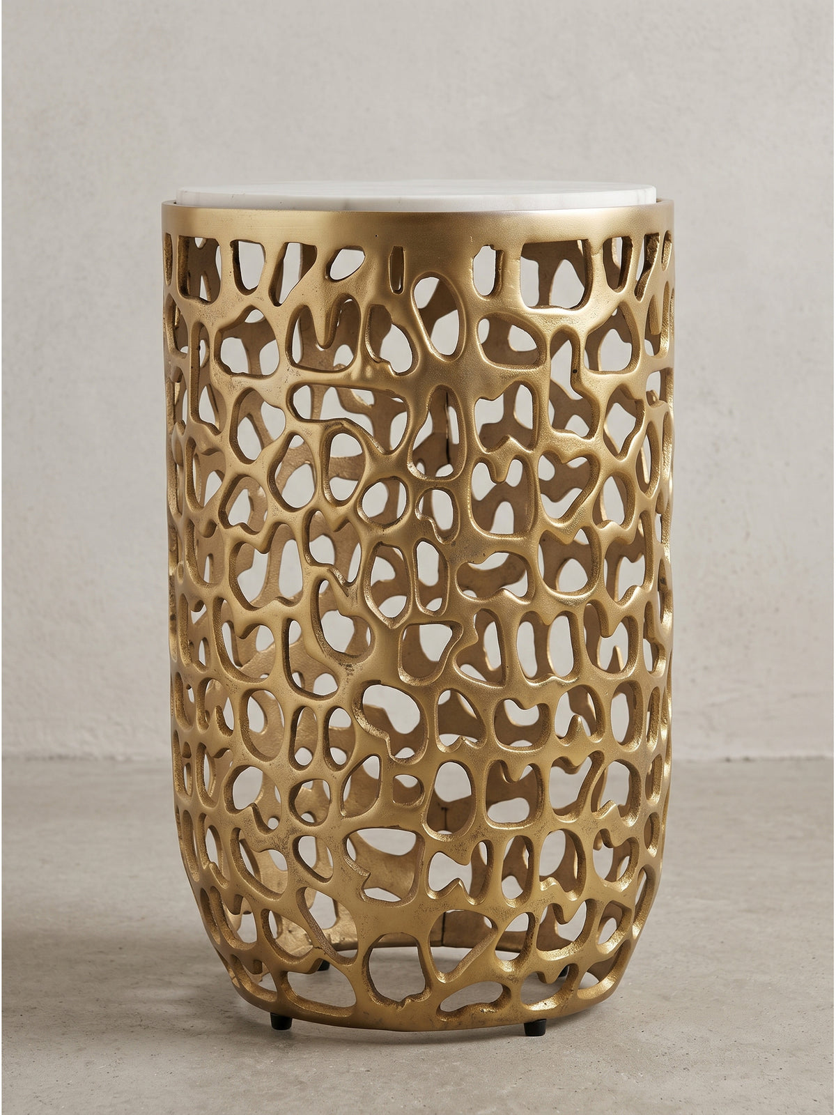 Seitenansicht des goldenen Beistelltisches mit durchbrochenem Design und heller Marmorablage vor weißem Hintergrund_
