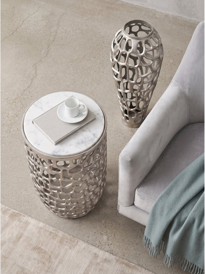 Draufsicht auf den runden Anstelltisch mit weißer Marmorplatte auf Eichenparkett neben einem Sessel mit Leselampe_