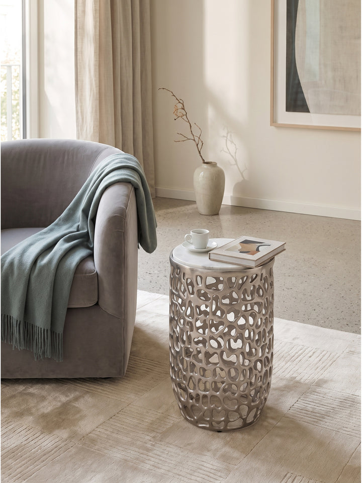 Silberner Metalltisch mit Marmor als skulpturaler Akzent im modern klassischen Wohnbereich neben einem Samtsofa_