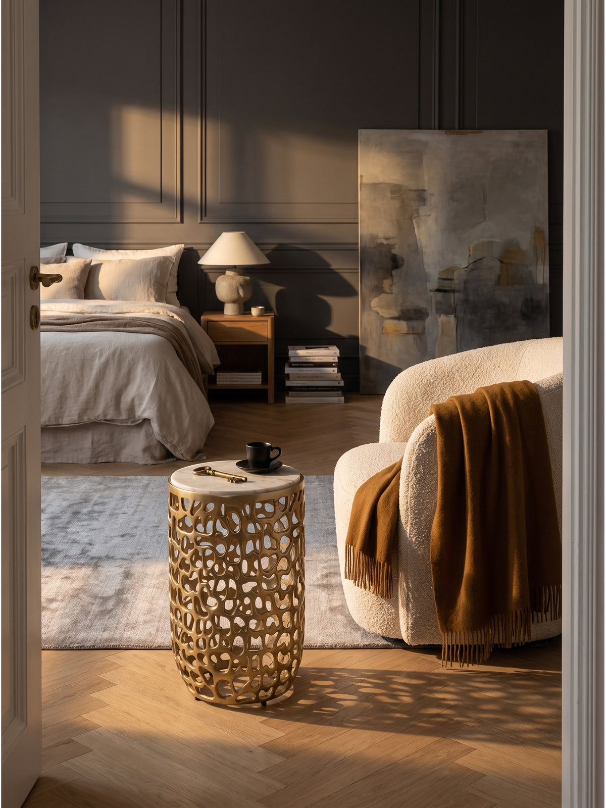 Runder Beistelltisch aus goldfarbenem Aluminium mit Marmorplatte 30x30x50 cm im eleganten Wohnzimmer neben einem Sessel auf Fischgrätparkett_