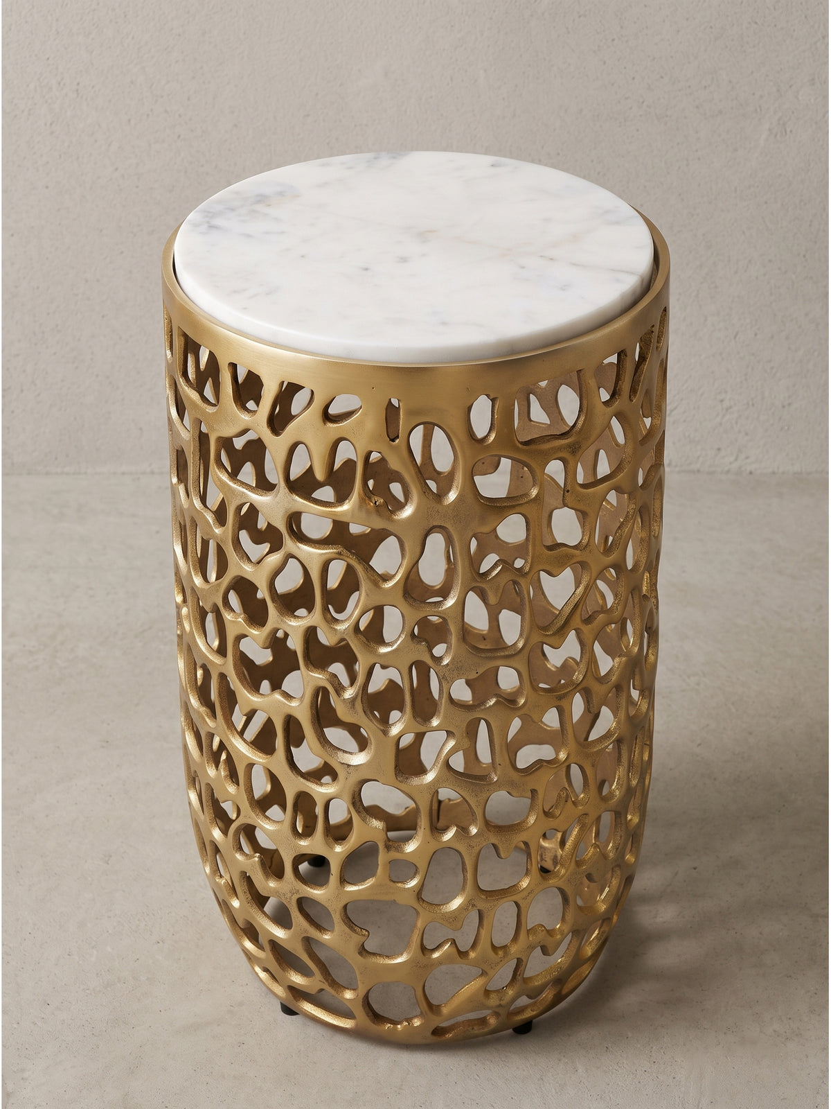 Runder Beistelltisch mit organischem Metallgestell in Gold und massiver Marmorplatte im Studio von schräg links gesehen_
