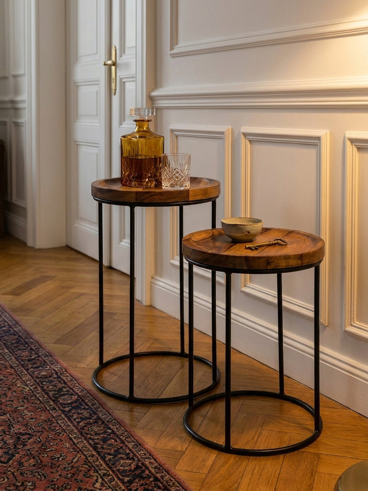 Ein bernsteinfarbener Glaskrug und ein Kristallglas stehen auf dem kleinen Couchtisch aus Massivholz vor einer Wand mit Boiserie-Panels._