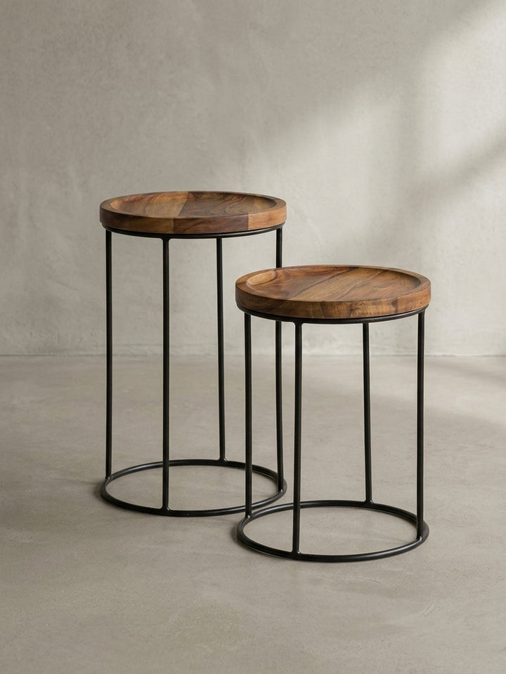 Zwei minimalistische Kaffeetische aus dunklem Massivholz und Eisen zeigen ihre puristische Silhouette vor neutralem Hintergrund._