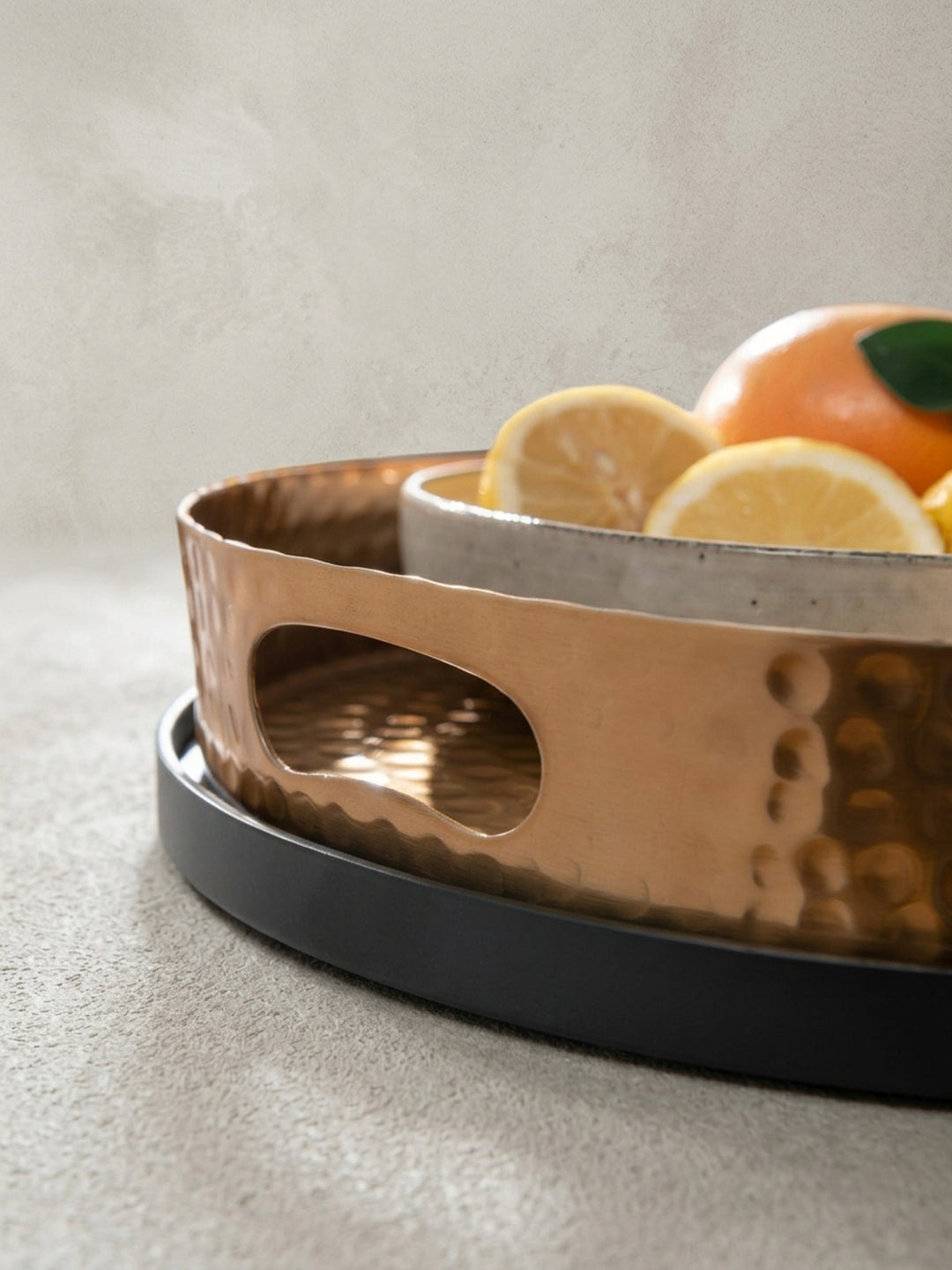 Nahaufnahme des integrierten Griffs im goldenen Tablett, ein praktisches Detail des abnehmbaren Couchtisches mit Hammerschlag-Finish._