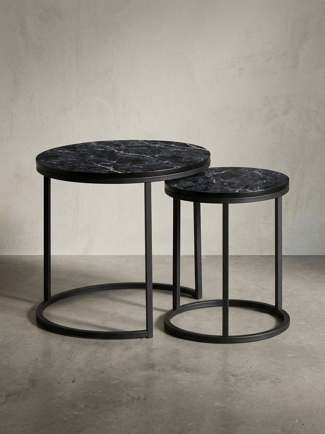 Design Beistelltisch 2er Set freigestellt auf weißem Hintergrund. Die runden Tische mit schwarzem Metallgestell und Tischplatte in Marmor-Optik sind klar zu sehen._