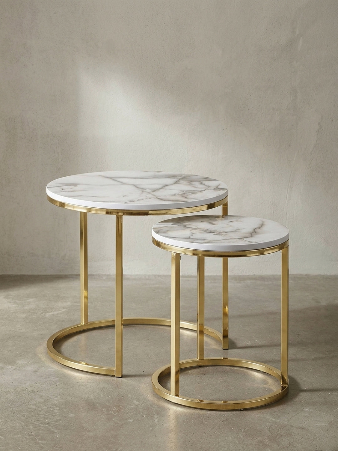 Frontalansicht des zweiteiligen Satztisch-Sets in weißer Marmor-Optik mit glänzenden goldfarbenen Metallbeinen vor neutralem Hintergrund_