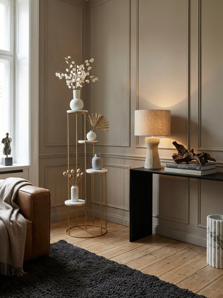 Blumenständer aus weißem Marmor und Gold in einem hellen Wohnzimmer, als elegantes Pflanzenregal neben einem Fenster stilvoll arrangiert._